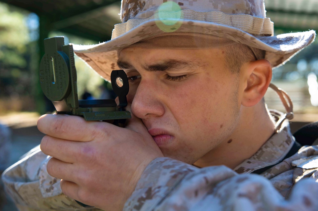 A Marine looks through a compass.