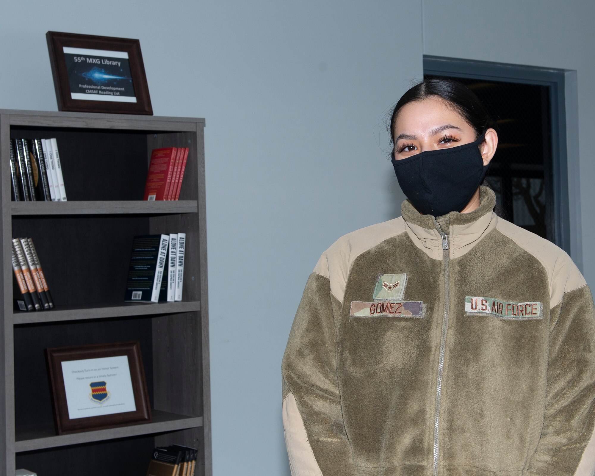 photograph of airman standing in front of a book shelf with books in it