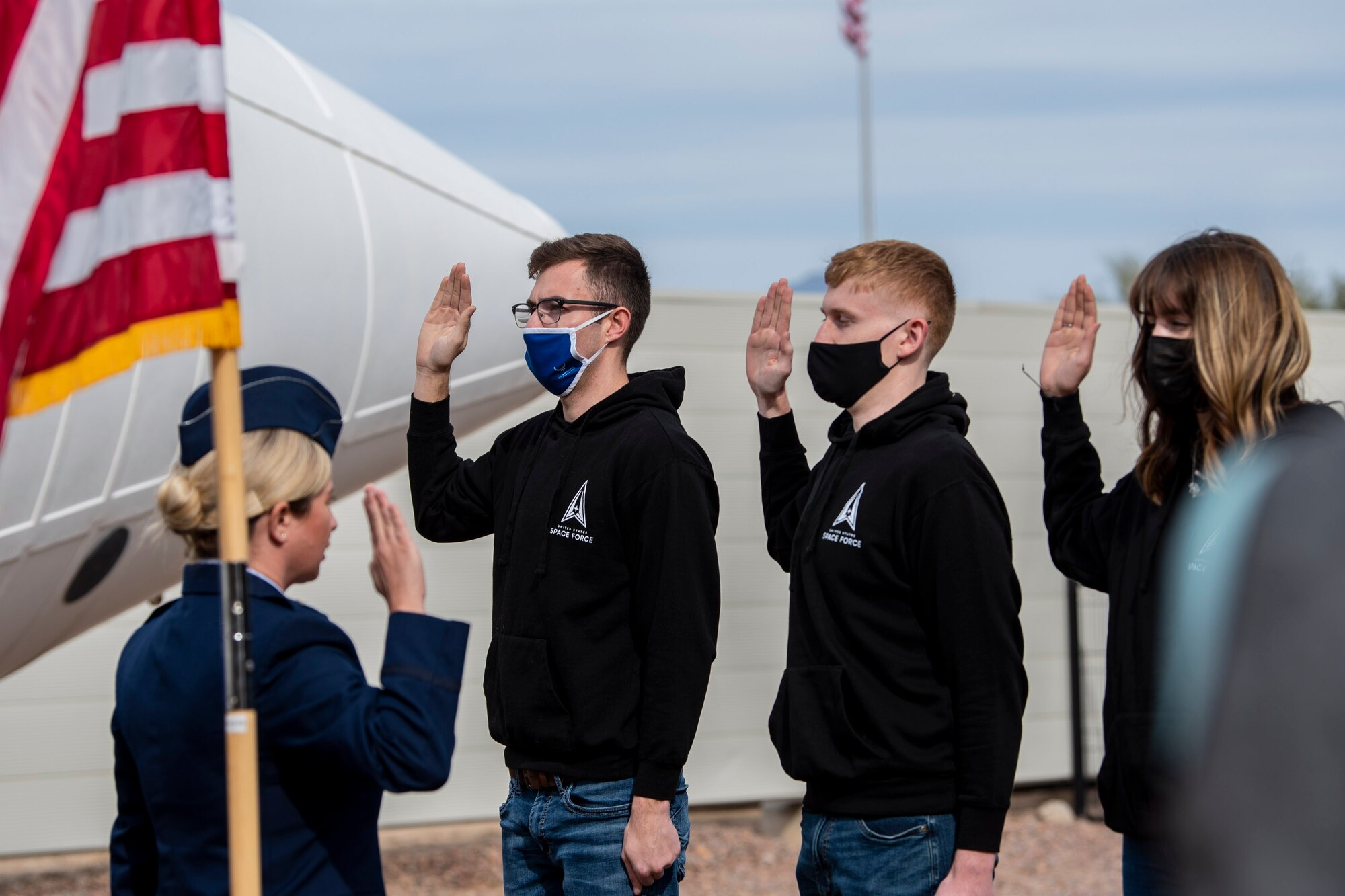 People raise their right hand during a ceremony.