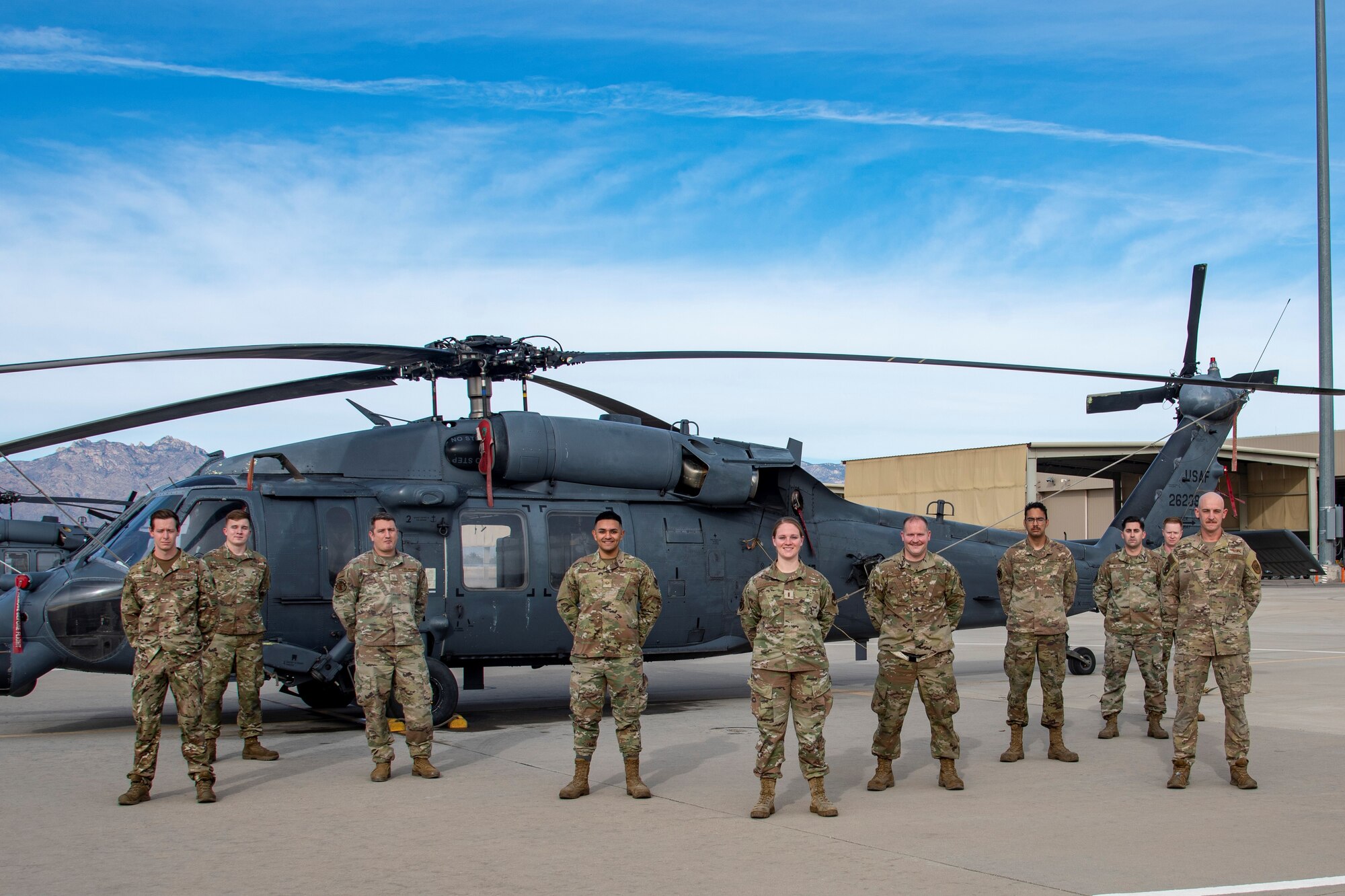 Airmen pose for a photo in front of a helicopter