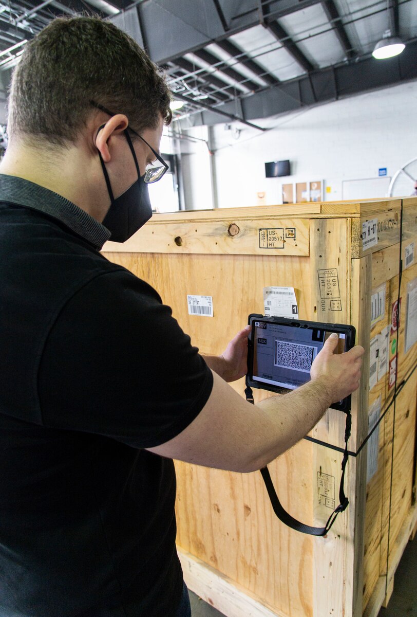 Vassili Koriabine, Cougaar Software Inc. software engineer, uses a tablet to scan a shipping label attached to a crate at Dover Air Force Base, Delaware, Nov. 18, 2021. In an effort to modernize the 2T2 career field as part of the Aerial Port of the Future initiative, the 436th Aerial Port Squadron was selected for CALBT testing due to its location and daily cargo movement. (U.S. Air Force photo by Roland Balik)