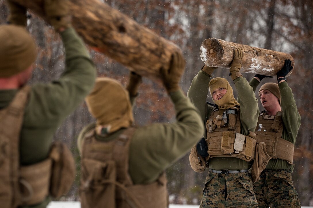 A group of Marines lift logs above their heads.