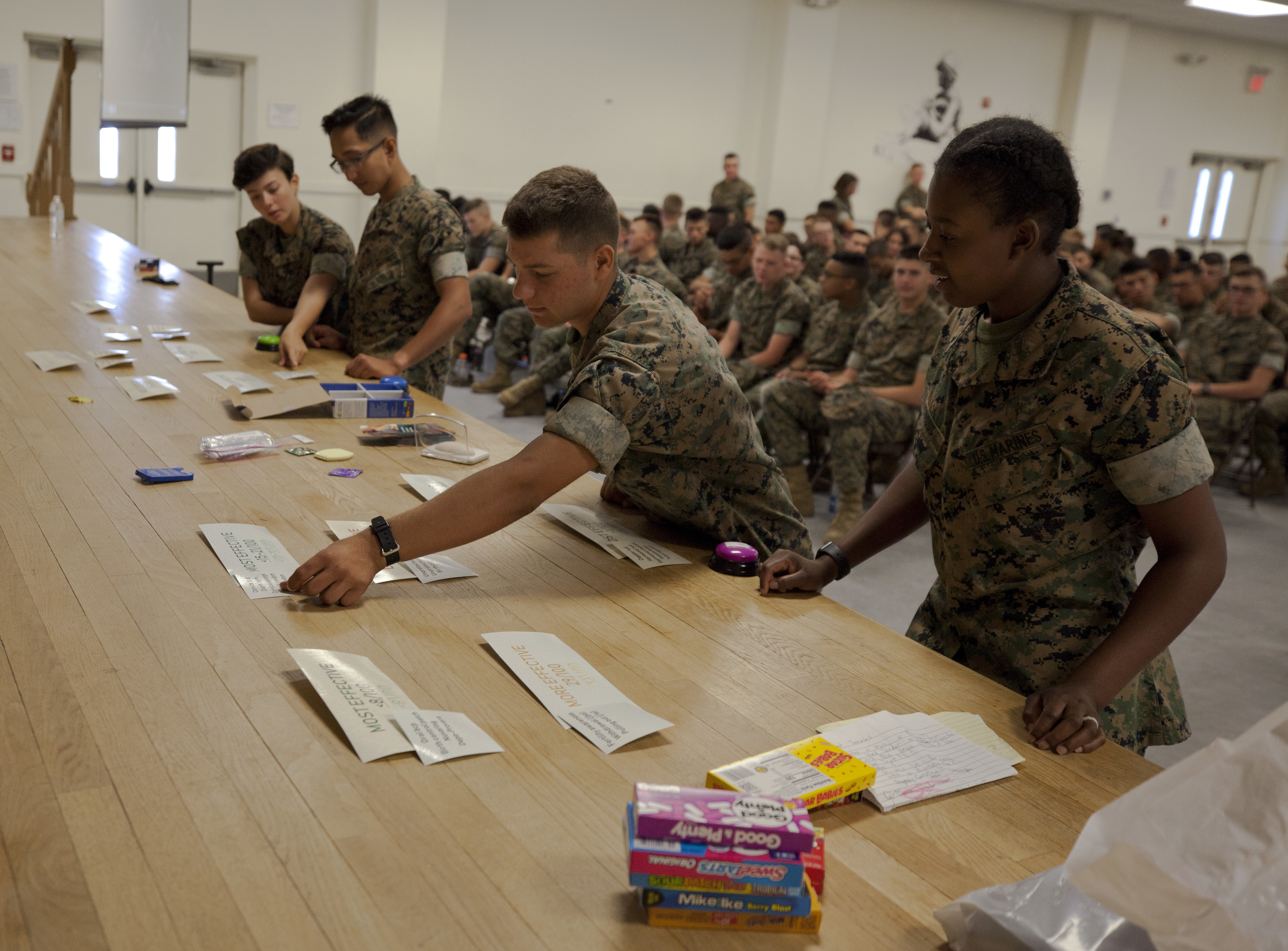 Marines sorting cards on a table in an auditorium.