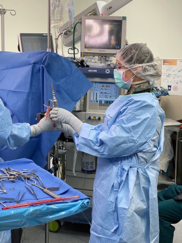 A woman in operating scrubs assists during  surgery.