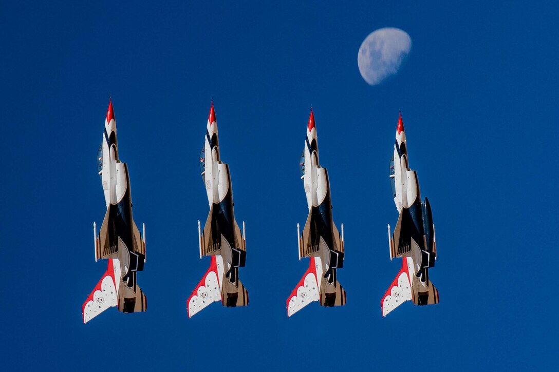 Four aircraft fly in vertical formation with the moon just above.
