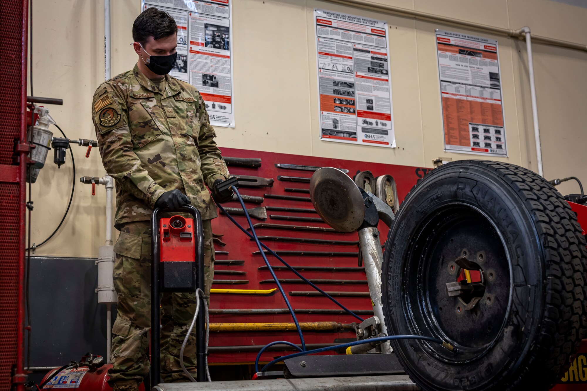 Airman inflating tire with air.