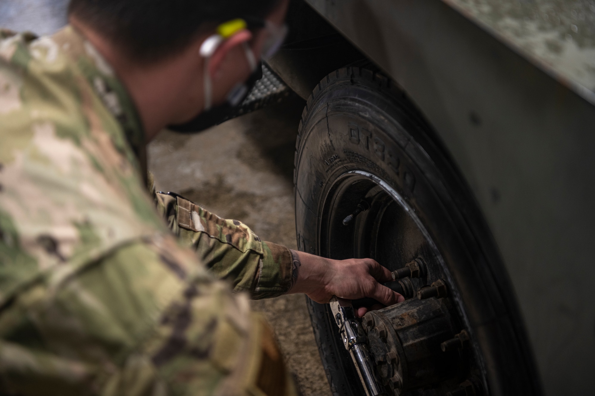 Airman using a torque wrench to tighten a screw nut on a truck.