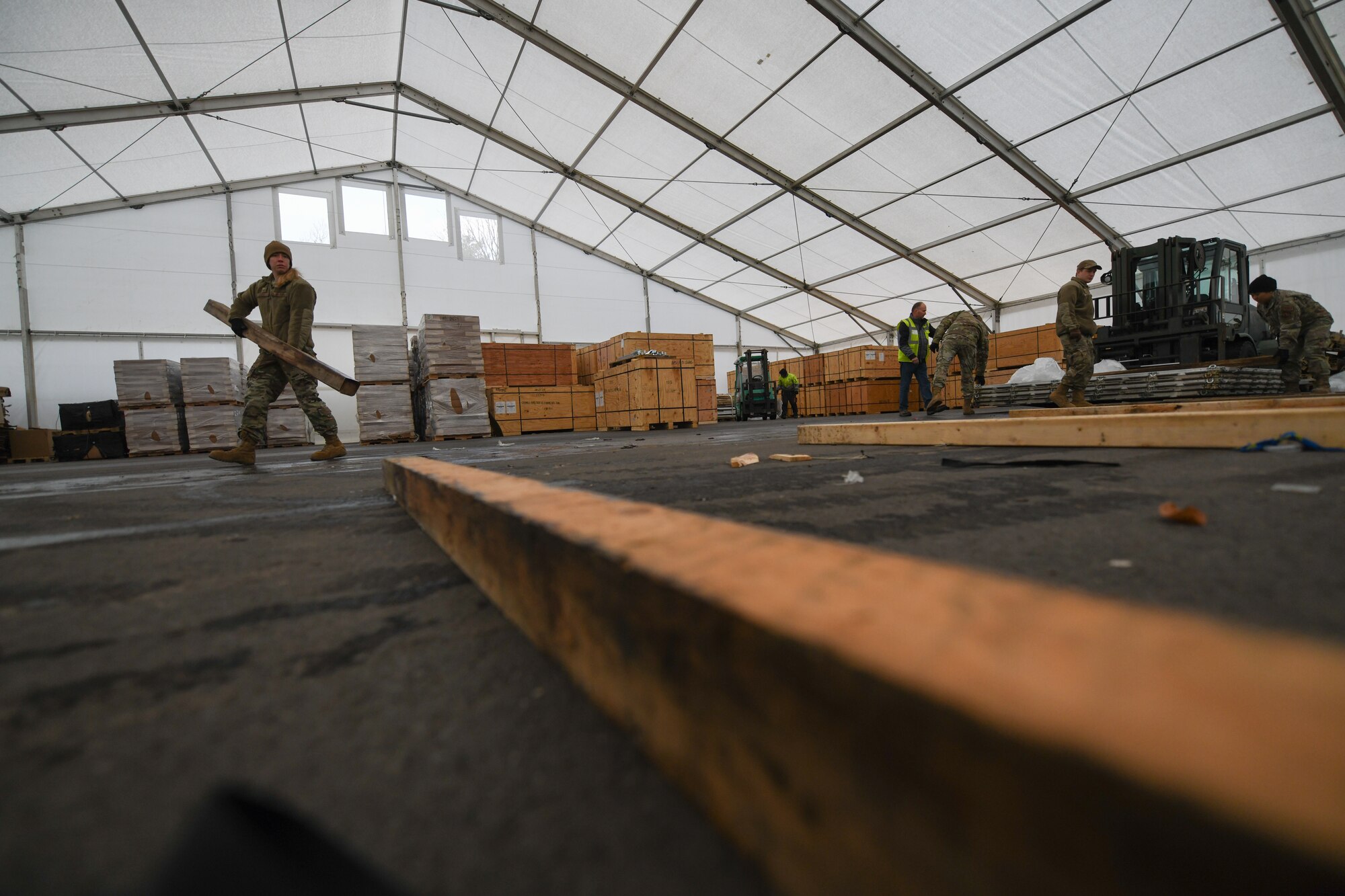 U.S. Air Force Staff Sgt. Holly Gibbs, 435th Air Expeditionary Wing air transportation craftsman, carries a four-by-four piece of dunnage to rest a pallet on at Ramstein Air Base, Germany, Jan 21, 2022. During a flood, U.S. and allied service member tents were damaged at Nigerien Air Base 101 and 201, which required replacements. The 435th AEW ensures Airmen have the resources to support counter-violent extremist operations in Africa and meet the demands of assigned missions. (U.S. Air Force photo by Senior Airman Ericka A. Woolever)