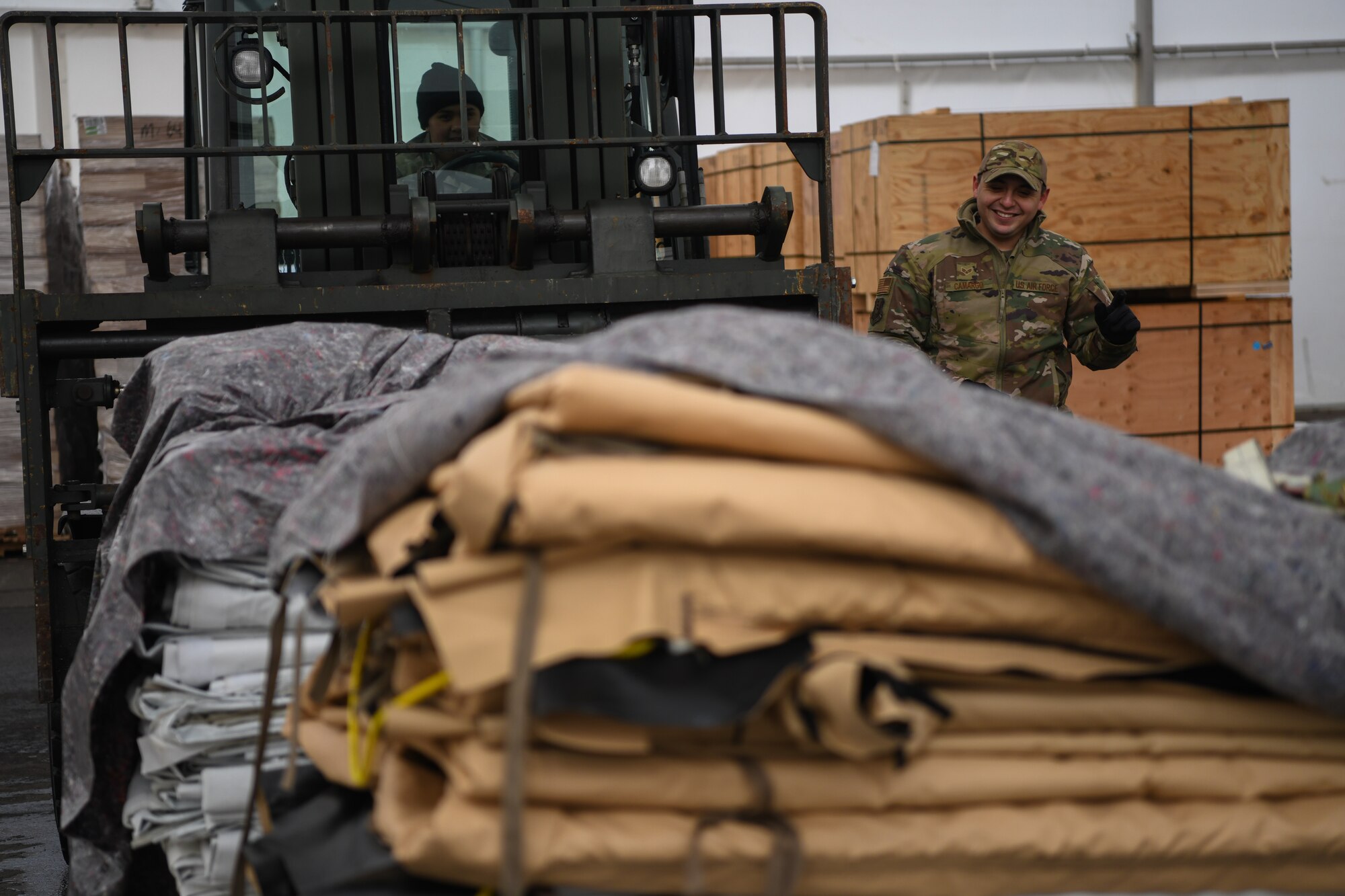 Senior Airman David Camargo, 435th Air Expeditionary Wing air transportation journeyman, right, spots U.S. Air Force Staff Sgt. Louise Thornton, 435th AEW air transportation craftsman, left, as she drives a 10K Standard Forklift carrying tent skins and liners for Nigerien Air Base 101 and 201 at Ramstein Air Base, Germany, Jan 21, 2022. During a flood, U.S. and allied service member tents were damaged, which required approximately 15 new replacements. (U.S. Air Force photo by Senior Airman Ericka A. Woolever)