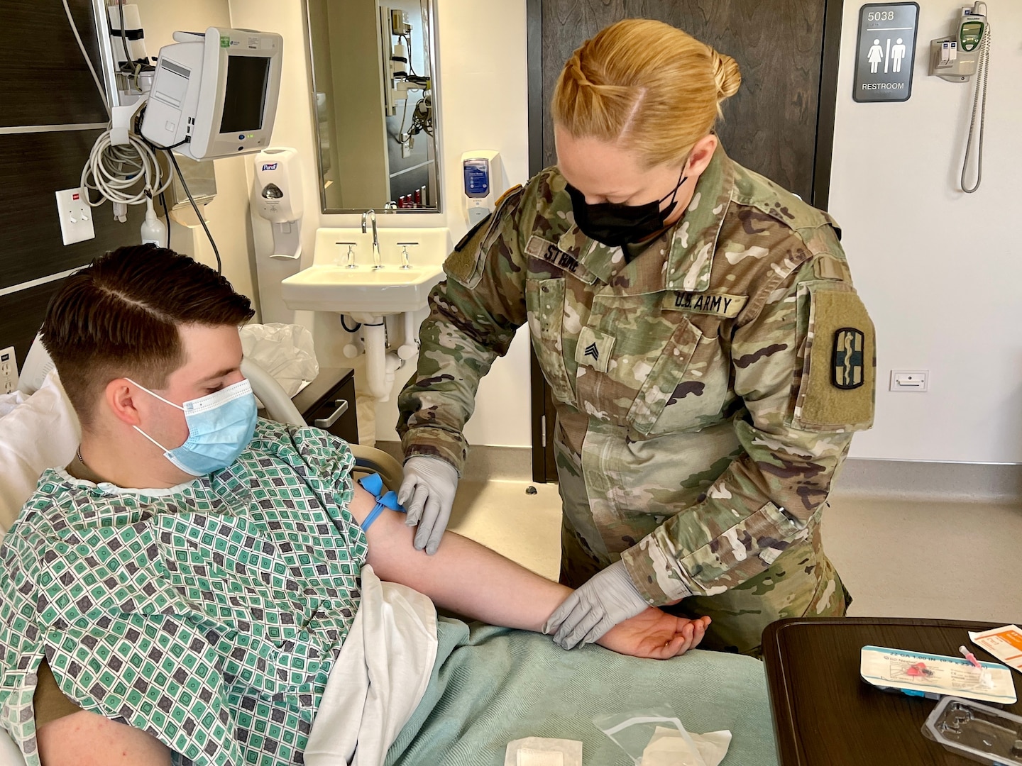 Sgt. Jenna Stroke, licensed practical nurse with the 433rd Medical Detachment, 115th Field Hospital, 32nd Hospital Center, prepares to administer fluids intravenously to Sgt. Jacob Phelps during the medical skills readiness rotation hosted by Bayne-Jones Army Community Hospital.