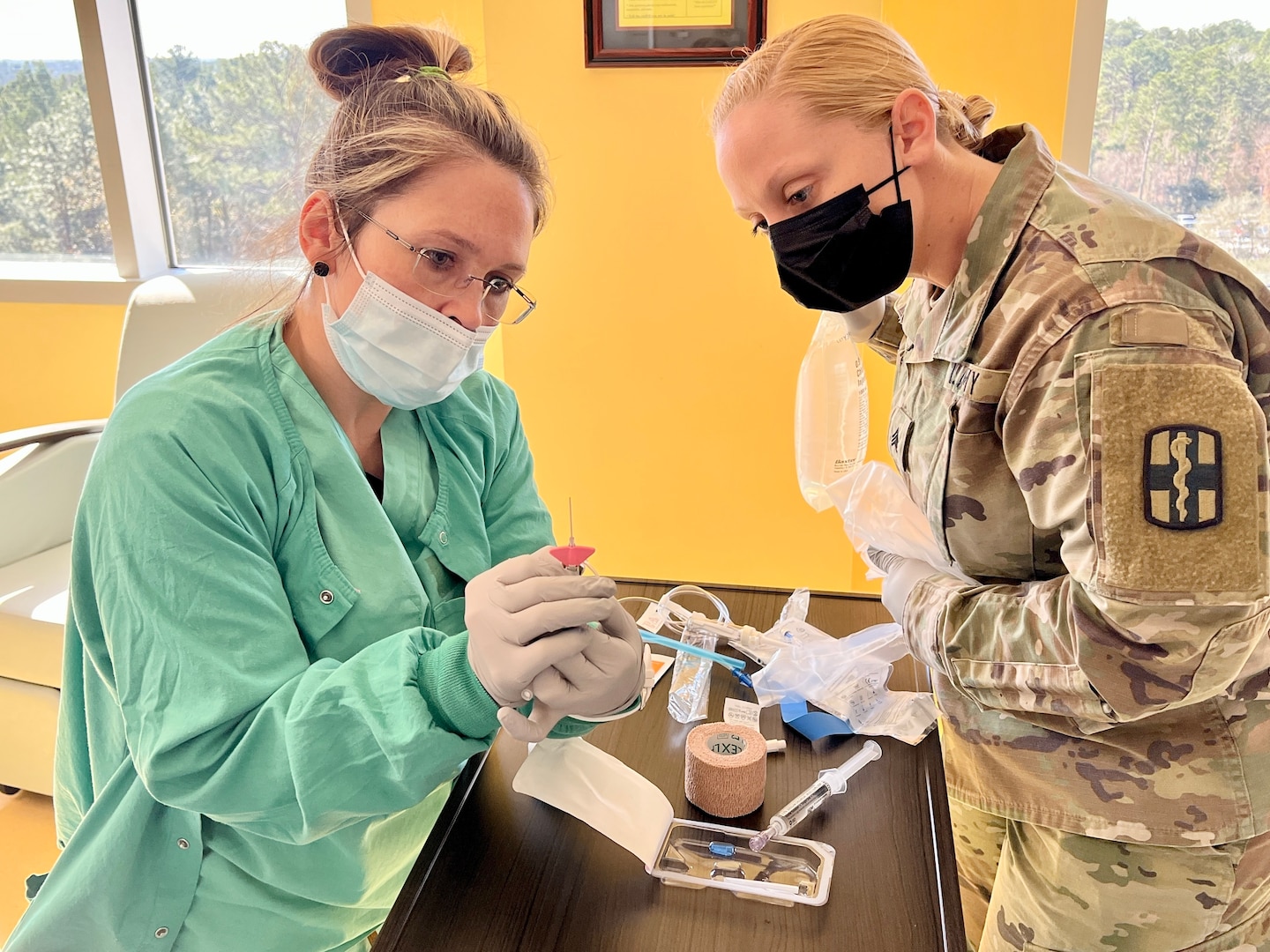 April Runyon discusses how to use new intravenous therapy needles with Sgt. Jenna Stroke, licensed practical nurse with the 433rd Medical Detachment, 115th Field Hospital, 32nd Hospital Center during the medical skills readiness rotation hosted by Bayne-Jones Army Community Hospital on Jan. 18, at the Joint Readiness Training Center and Fort Polk, Louisiana.