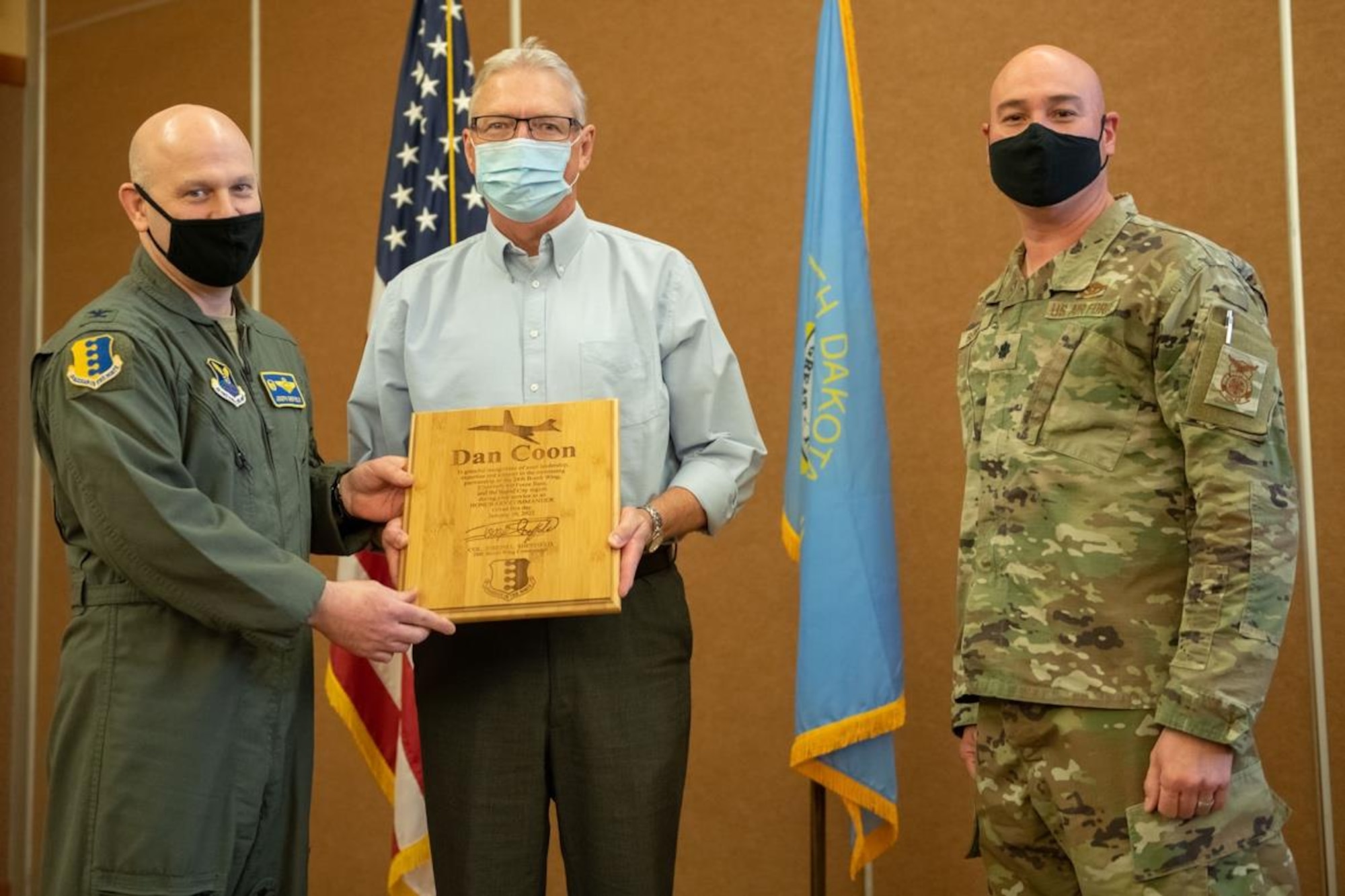 Col. Joseph Sheffield, 28th Bomb Wing commander (left), and Lt. Col. David Berrios, 28th Civil Engineer Squadron commander (right), present Dan Coon, former operation management engineer for the City of Rapid City, with a plaque in appreciation for his time as the 28th CES honorary commander during a special hail and farewell event at The Monument Convention Center in Rapid City, S.D., Jan. 19, 2022.