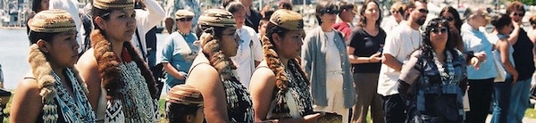 A mixed crowd of male and females watch a tribal ceremony.