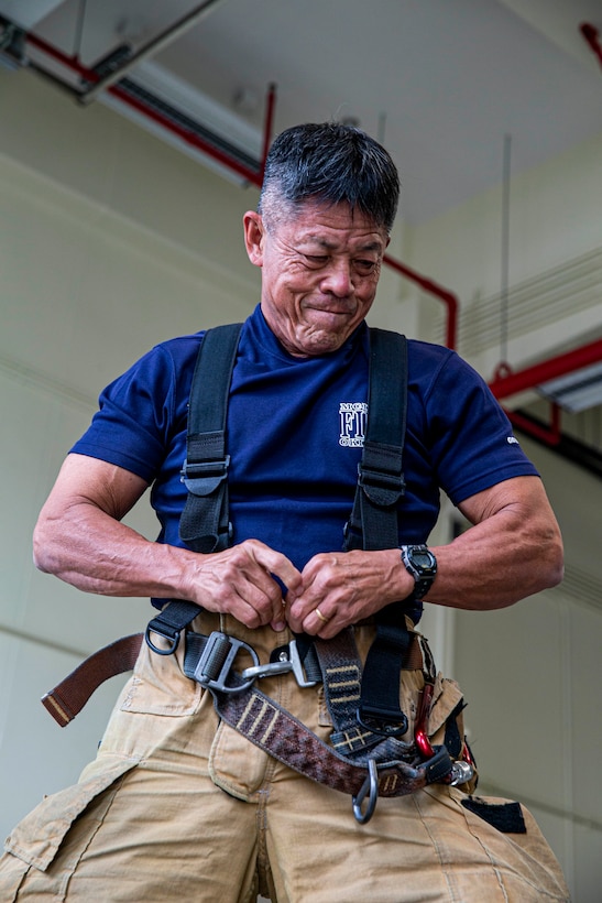 A firefighter puts on pieces of his uniform.