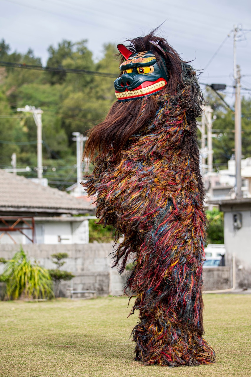 A person stands in a field in a lion costume.