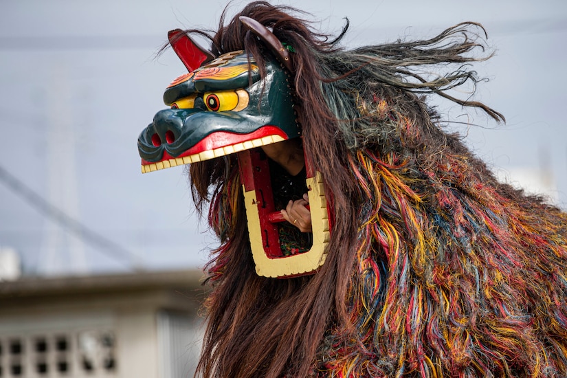 A man's hands are visible inside as large lion costume he's wearing while dancing.