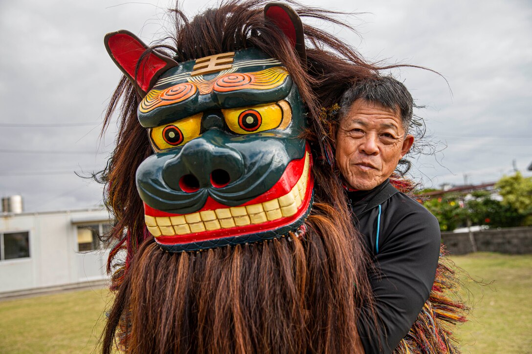 A man holds up a giant head of a lion costume.