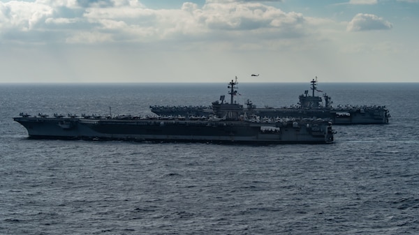 220122-N-PQ495-1064 PHILIPPINE SEA (Jan. 22, 2022) Nimitz-class aircraft carrier USS Carl Vinson (CVN 70), front, and Nimitz-class aircraft carrier USS Abraham Lincoln (CVN 72), transit the Philippine Sea while escorted by an MH-60S Sea Hawk, assigned to the “Black Knights” Helicopter Sea Combat Squadron (HSC) 4, Jan. 22, 2022. Operating as part of U.S. Pacific Fleet, units assigned to Carl Vinson and Abraham Lincoln Carrier Strike Groups, Essex and America Amphibious Ready Groups and Japan Maritime Self-Defense Force, are conducting training to preserve and protect a free and open Indo-Pacific region. (U.S. Navy photo by Mass Communication Specialist Seaman Larissa T. Dougherty)
