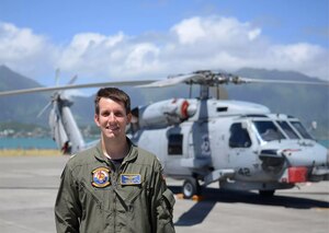 Navy pilot pictured in front of helicopter he flew for the service.