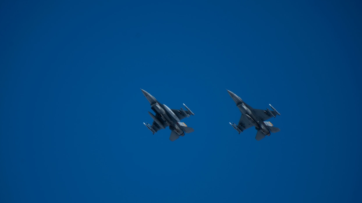 Two aircraft fly across a bright blue sky