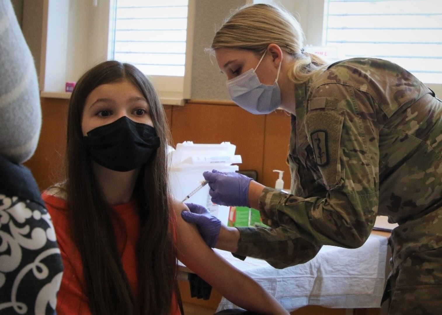 U.S. Army Spc. Kensey Frazee, Licensed Practical Nurse, 167th Medical Augmentation Detachment, 30th Medical Brigade, provides a COVID-19 Booster Vaccination to 13-year-old Heidi Hall at a Landstuhl Regional Medical Center COVID-19 Vaccination event, Jan. 6.