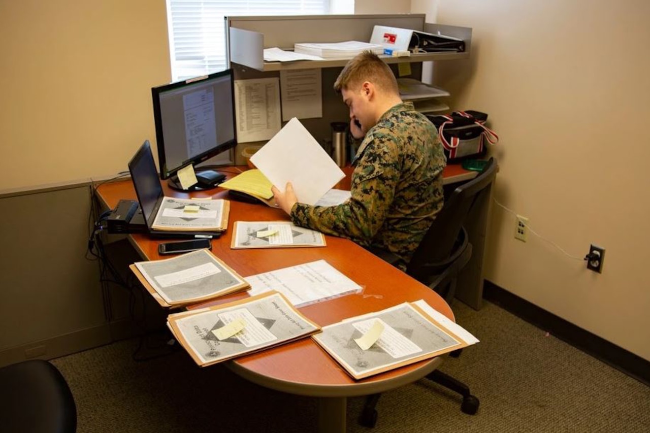 A Marine attached to a tax center works with a customer over the telephone.