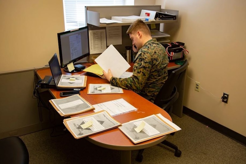 A Marine attached to a tax center works with a customer over the telephone.