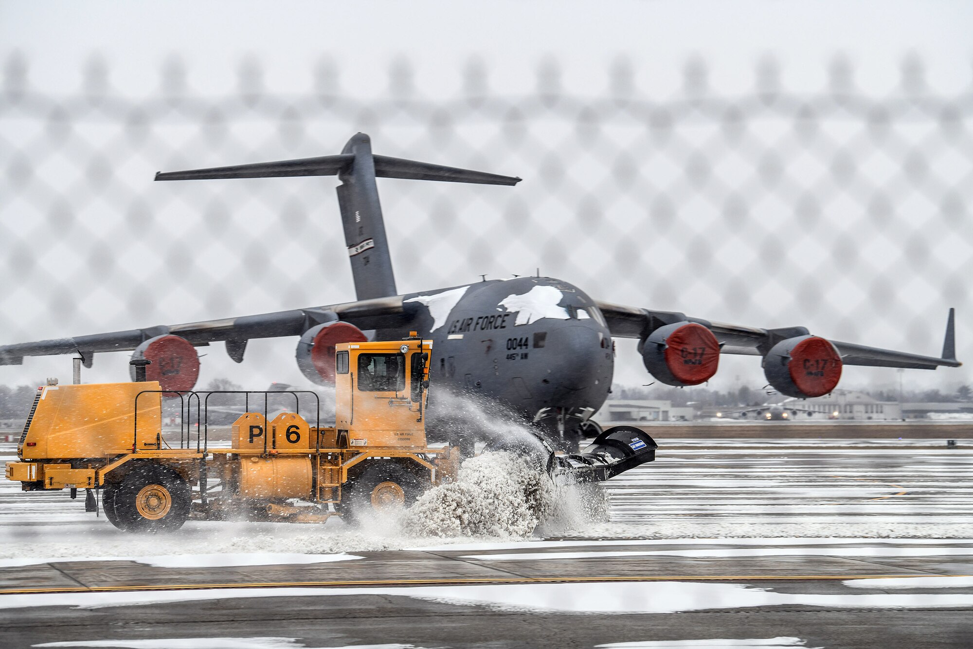 A snow plow works its way down the flight line at the 445th Airlift Wing Jan. 24, 2022, clearing away the snow surrounding the wing’s C-17 Globemaster III aircraft sitting on the ramp after a winter storm brought several inches of snow to the Dayton, Ohio, area.