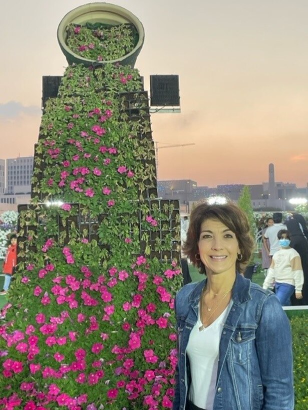 Woman poses in front of flower arrangement