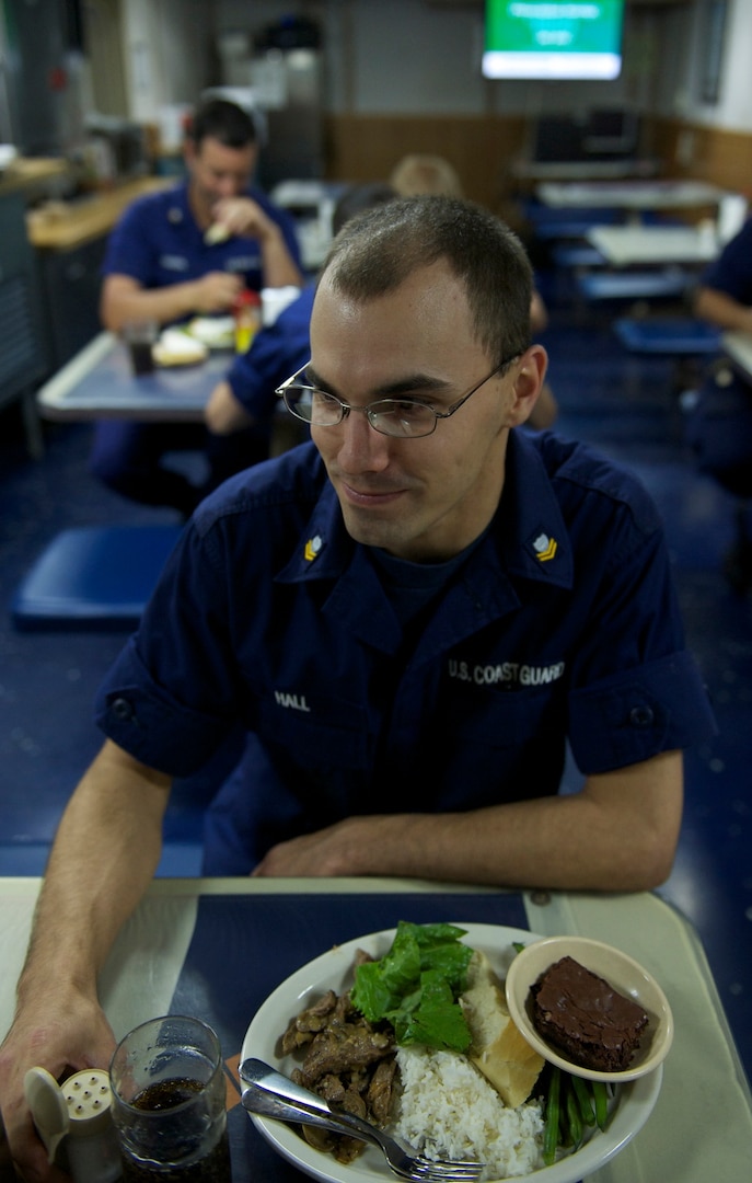 Petty Officer 2nd class Ty Hall takes a break during the workday to eat lunch on the mess deck with his shipmates. Food service specialists provide three meals a day to the Polar Star's crew. U.S. Coast Guard photo by Seaman Melissa McKenzie.