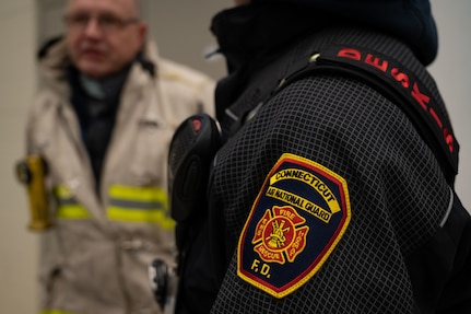 Firefighters converse during a training exercise hosted by the Connecticut Air National Guard Fire Department Dec. 10, 2021, at Bradley Air National Base, Conn. The CTANG Fire Department collaborated with mutual aid partners to incorporate resources from various fire departments into its incident command system.