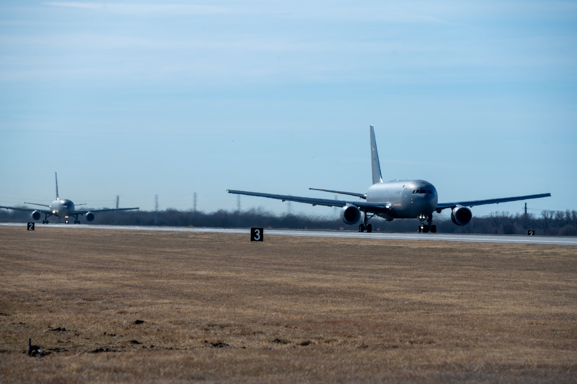 A KC-46A Pegasus takes off while another prepares to do the same as part of a minimum interval takeoff exercise Jan. 13, 2022, at McConnell Air Force Base, Kansas.