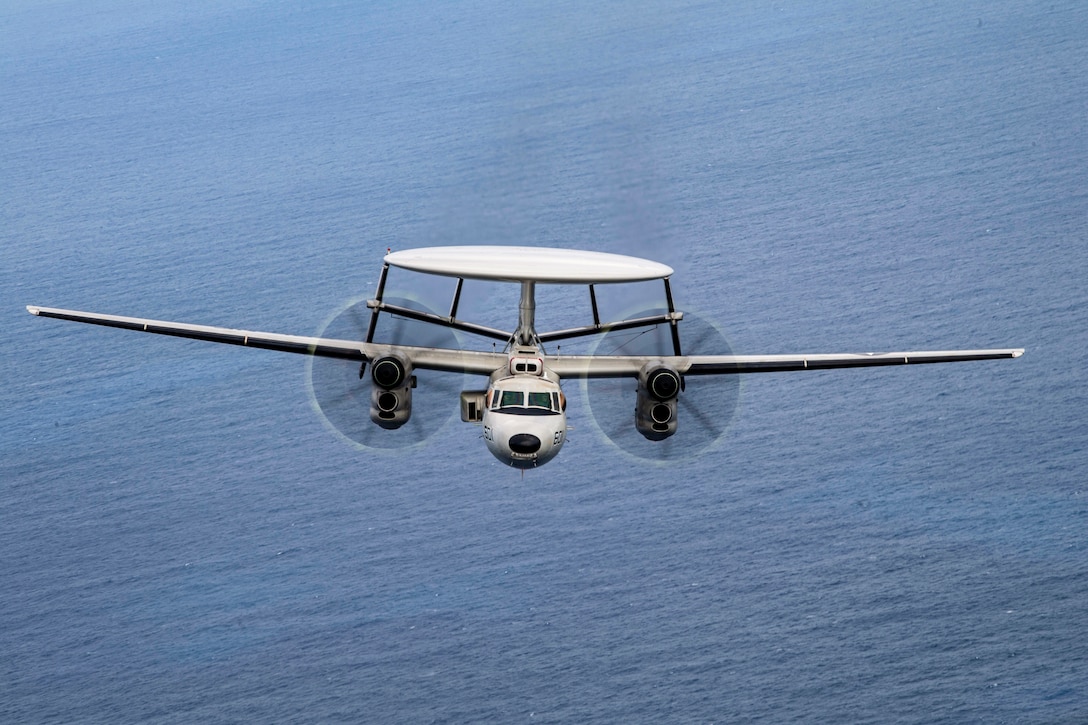 An aircraft flies over a body of water.