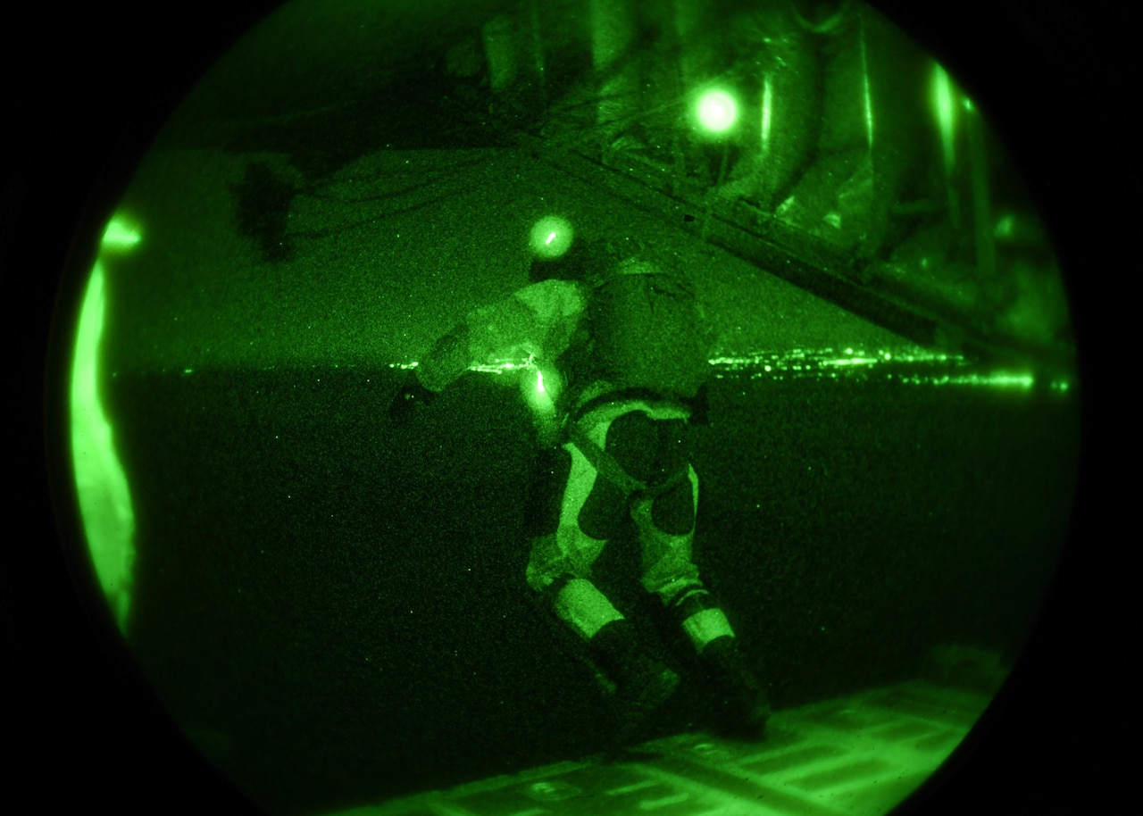 An airman jumps from an aircraft as seen by night vision goggles.