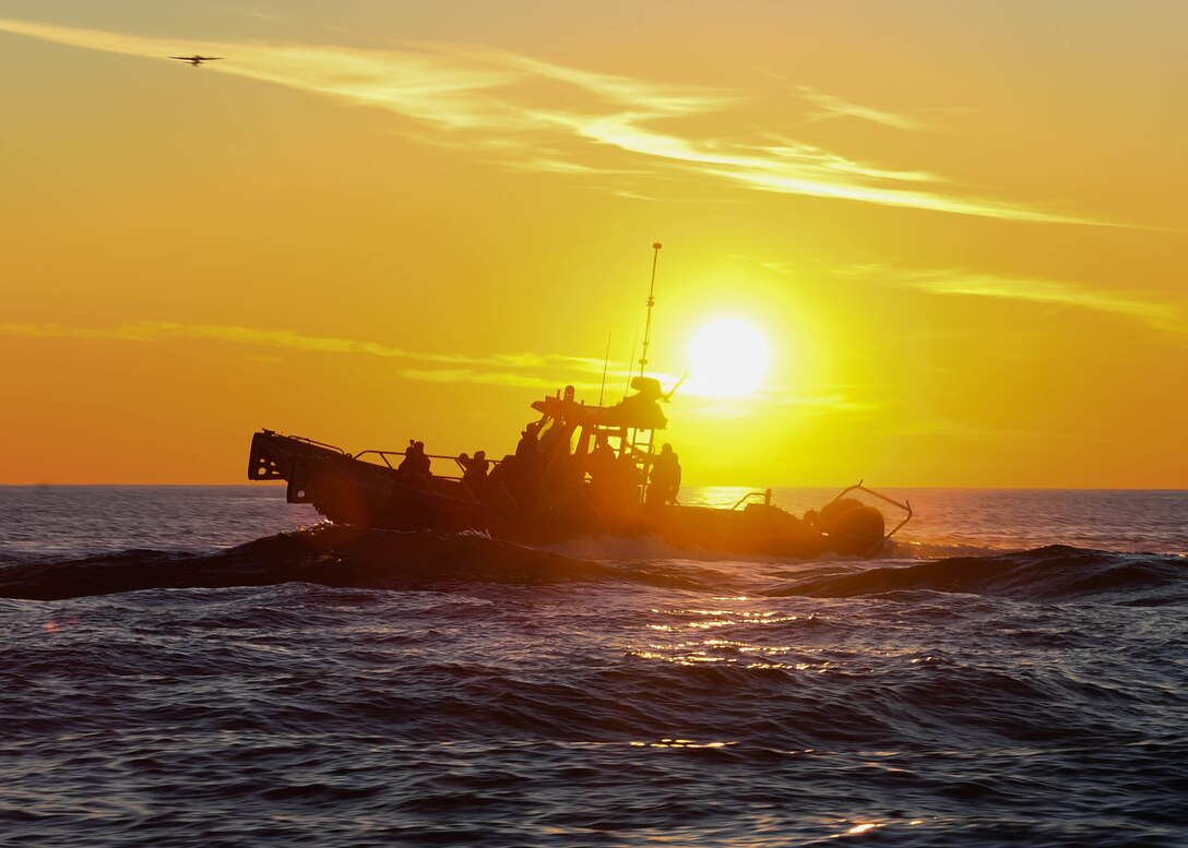 A ship sails under a sunlit sky.