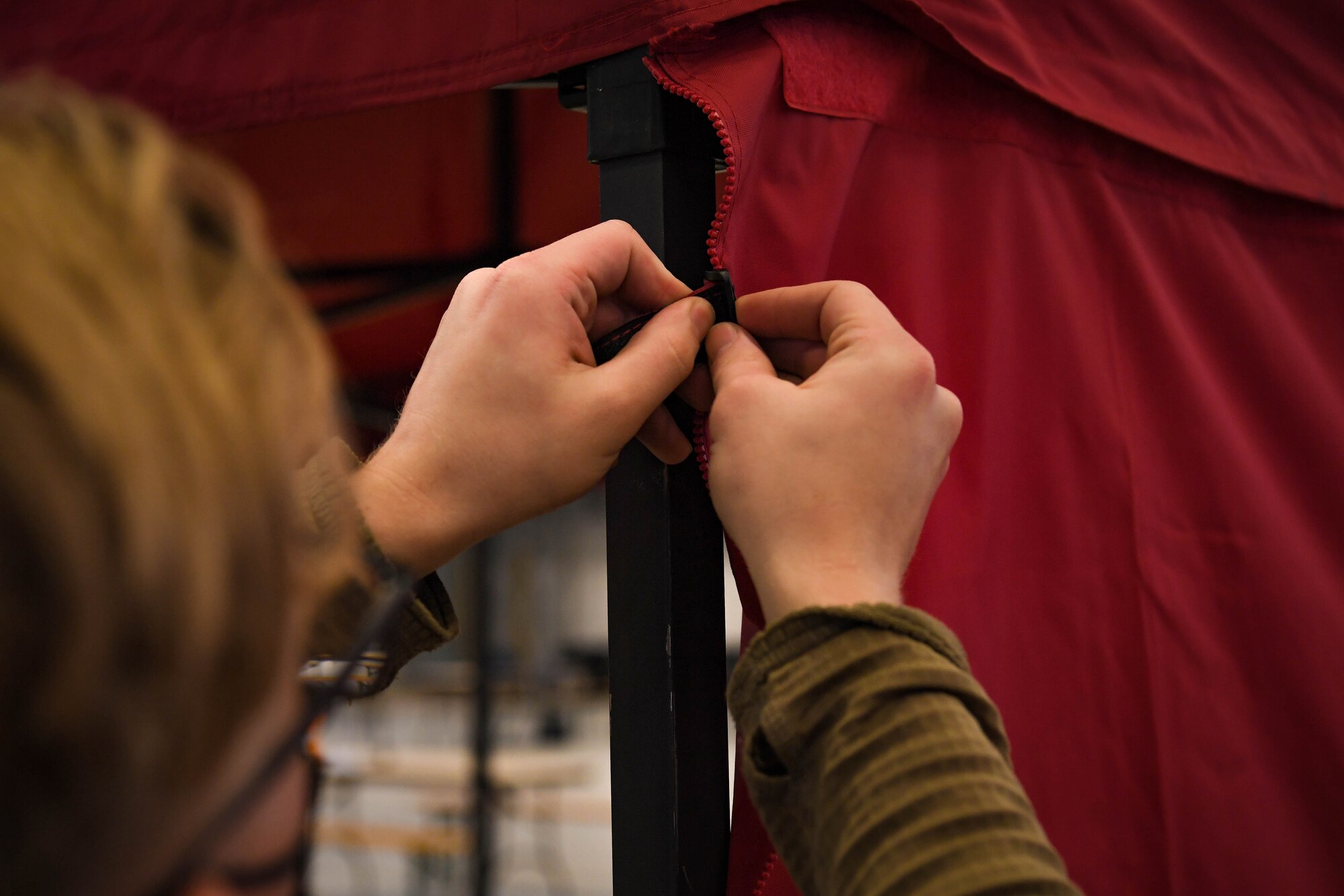 U.S. Air Force Airman 1st Class Tynan Mazur, 86th Maintenance Squadron aircraft fuel systems journeyman, sets up a tent at Ramstein Air Base, Germany, Jan. 25, 2022. Airmen assigned to RAB worked diligently to prepare Hangar three for the German Red Cross to enable them to administer the COVID-19 vaccine and booster shots to the local national workforce and U.S. and NATO personnel. (U.S. Air Force photo by Airman 1st Class Jared Lovett)