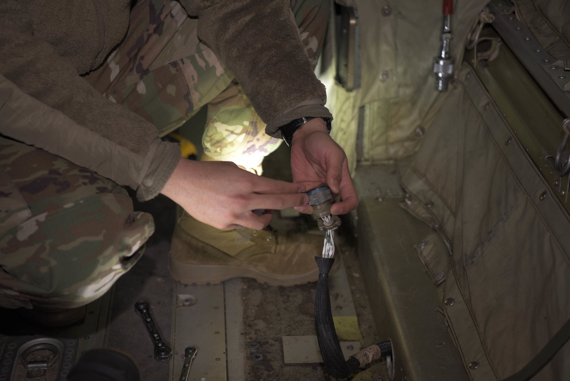 Airman tapes off electrical wires on aircraft.