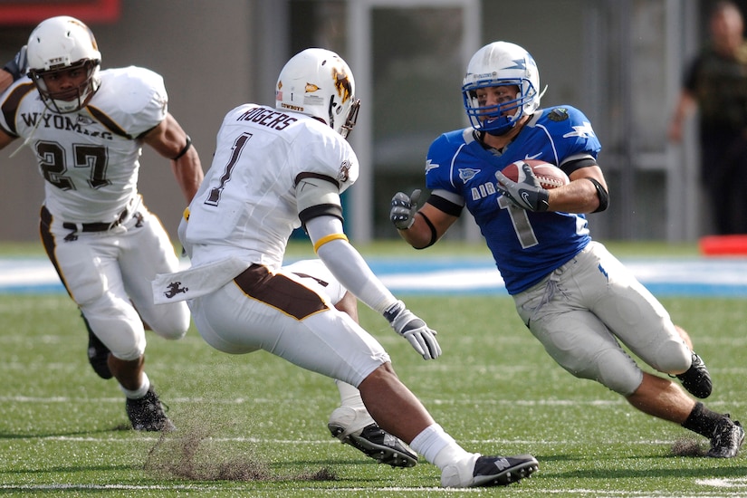 A football player rushes against two players.