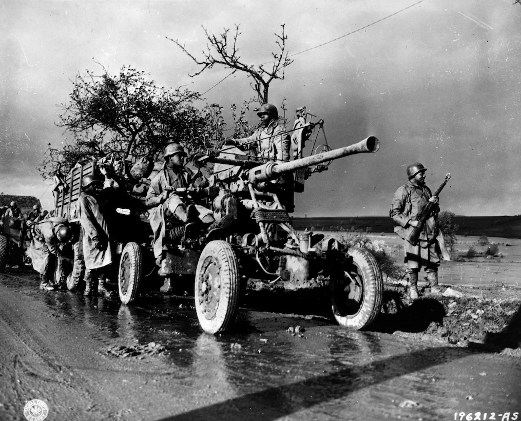 Soldiers move an artillery piece on a road.