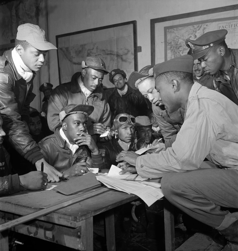 Airmen mill about a table.