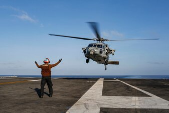 Aviation Electrician's Mate Airman Brian Aguirre directs an MH-60S Sea Hawk helicopter aboard USS Abraham Lincoln (CVN 72).