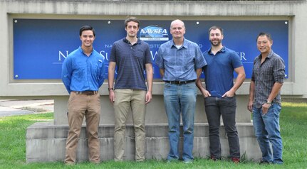 IMAGE: – Pre-emplaced Electric Vehicle Stopper (PEVS) Primary Engineer Kevin Arrington, PEVS Engineer Joshua Rawles, PEVS Project Lead David Dvorak, Booz Allen Hamilton Contract Engineer Kevin Komiensky and PEVS Technical Lead Dr. Yeong-Jer Chen stand in front of the NAVSEA Warfare Centers sign at Naval Surface Warfare Center Dahlgren Division.