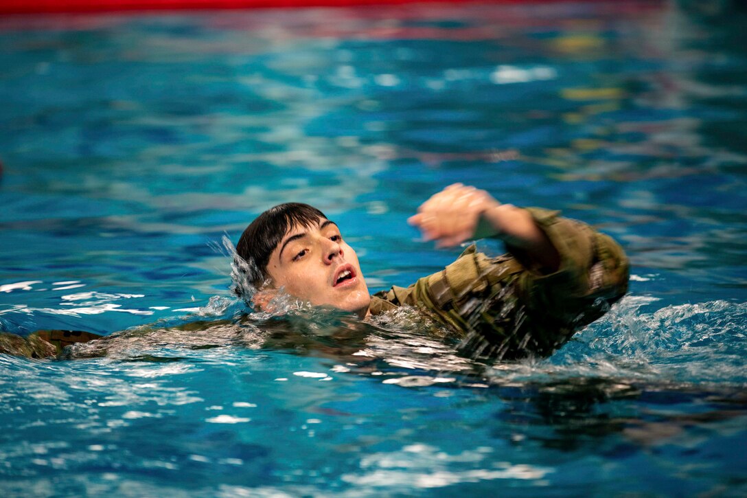 A soldier swims in a pool.