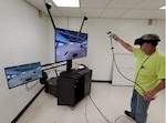 A painter at Marine Corps Logistics Base Albany, Ga., practices painting a virtual HMMWV hood.