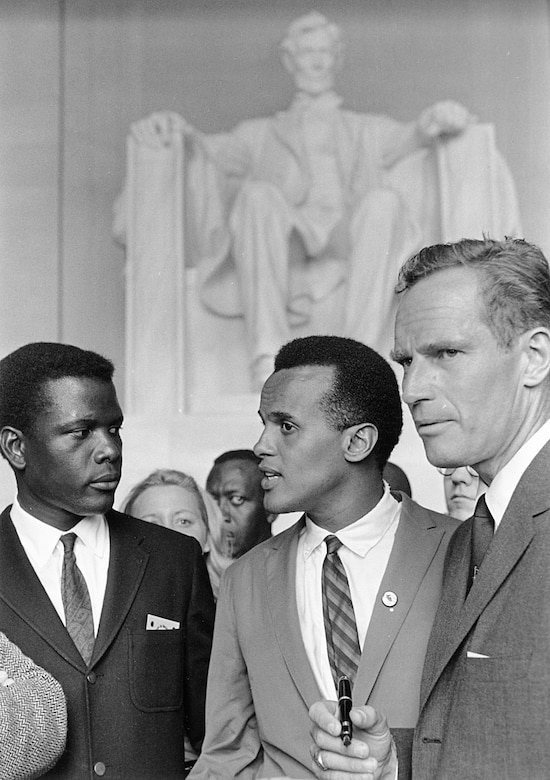 Three men stand in front of a crowd; the Lincoln Memorial is in the background.