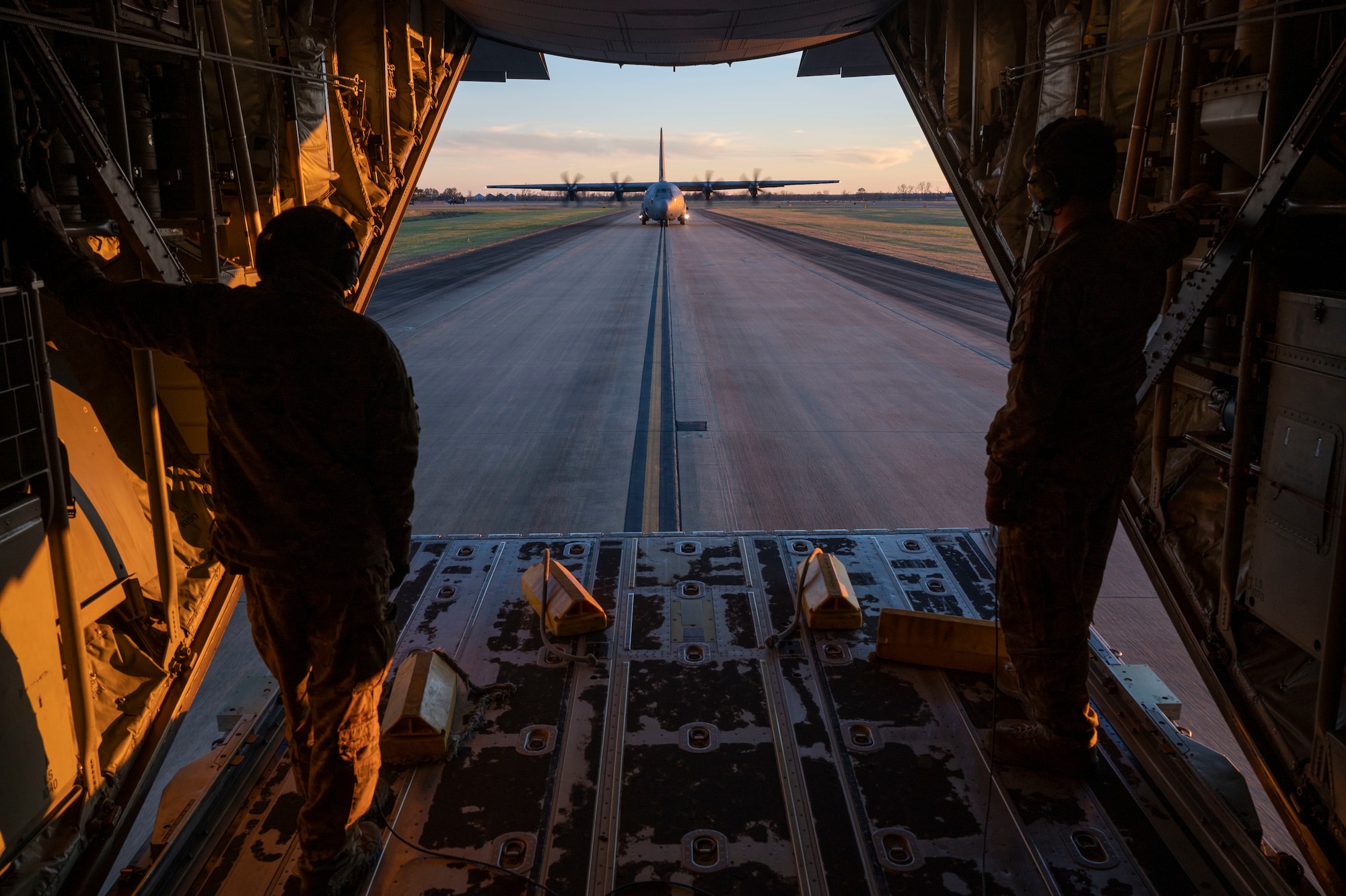 Loadmasters from the 317th Airlift Wing at Dyess Air Force Base, Texas, look out the back of a C-130J Super Hercules