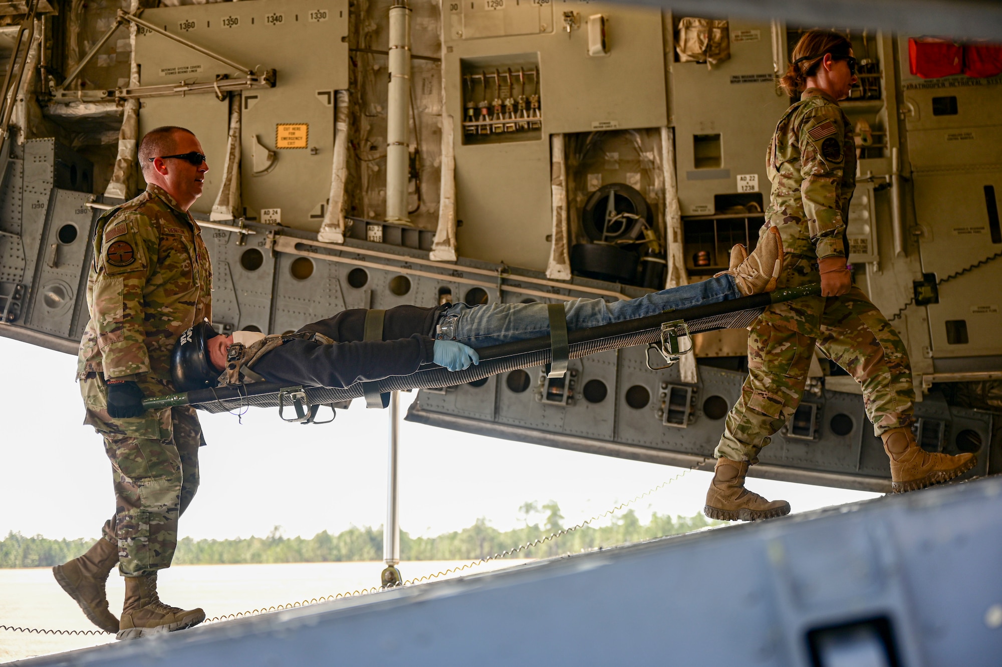Aeromedical evacuation technicians transport a patient with simulated injuries onto a C-17 Globemaster