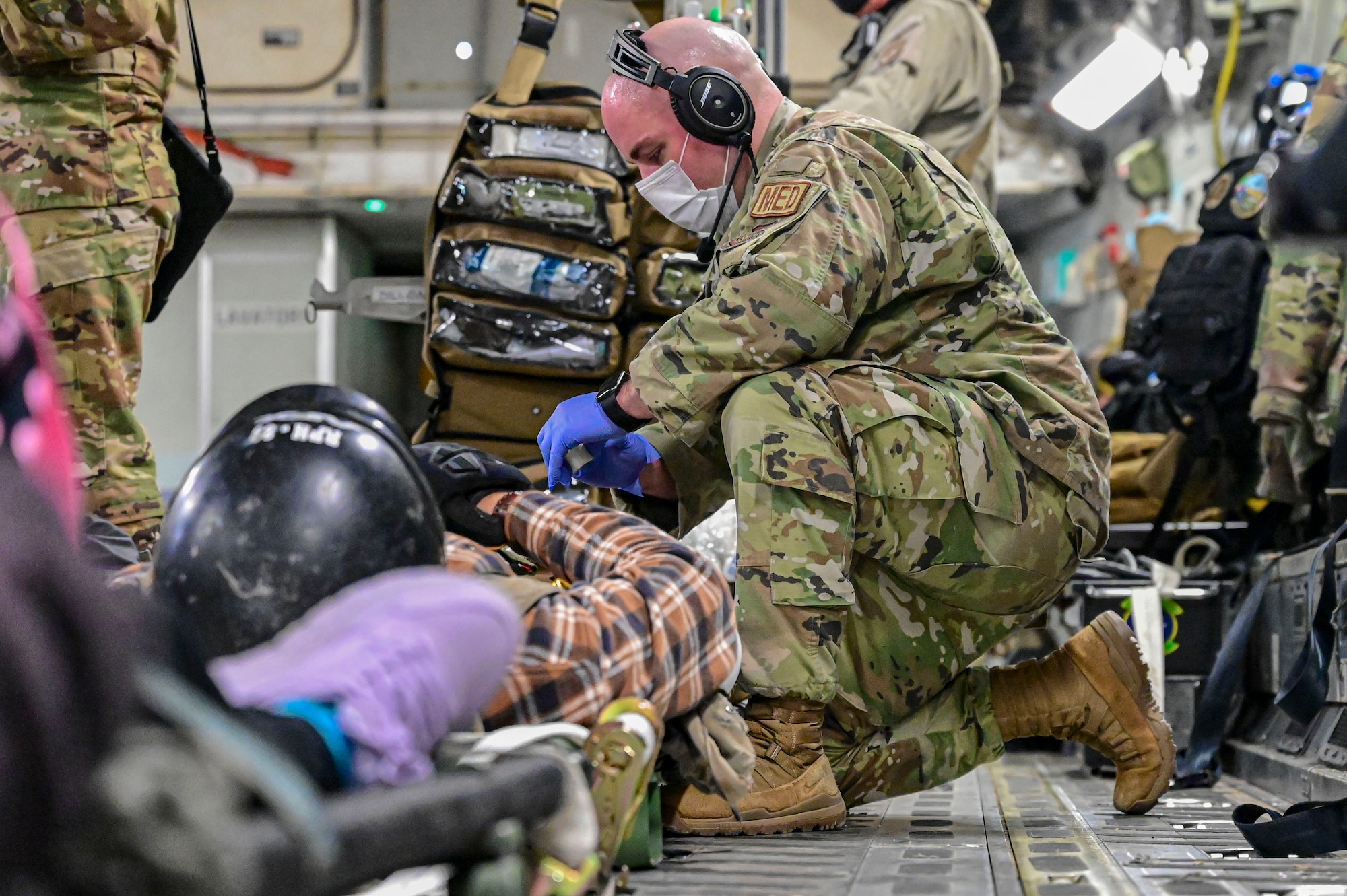 A person provides care to a patient with simulated injuries during an Aeromedical Evacuation exercise