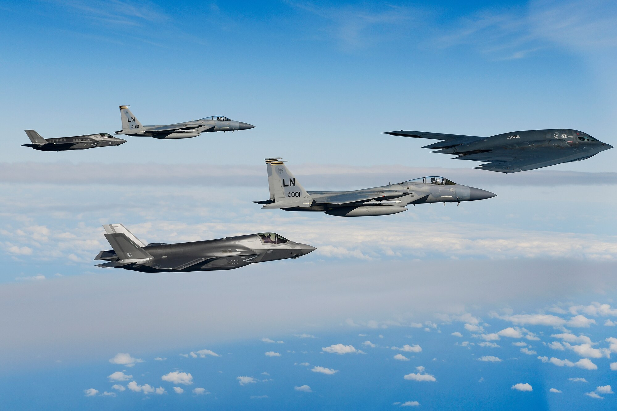 A B-2A Spirit bomber assigned to the 509th Bomb Wing leads a delta formation consisting of two F-15C Eagles assigned to the 48th Fighter Wing and two Royal Air Force F-35B Lightnings