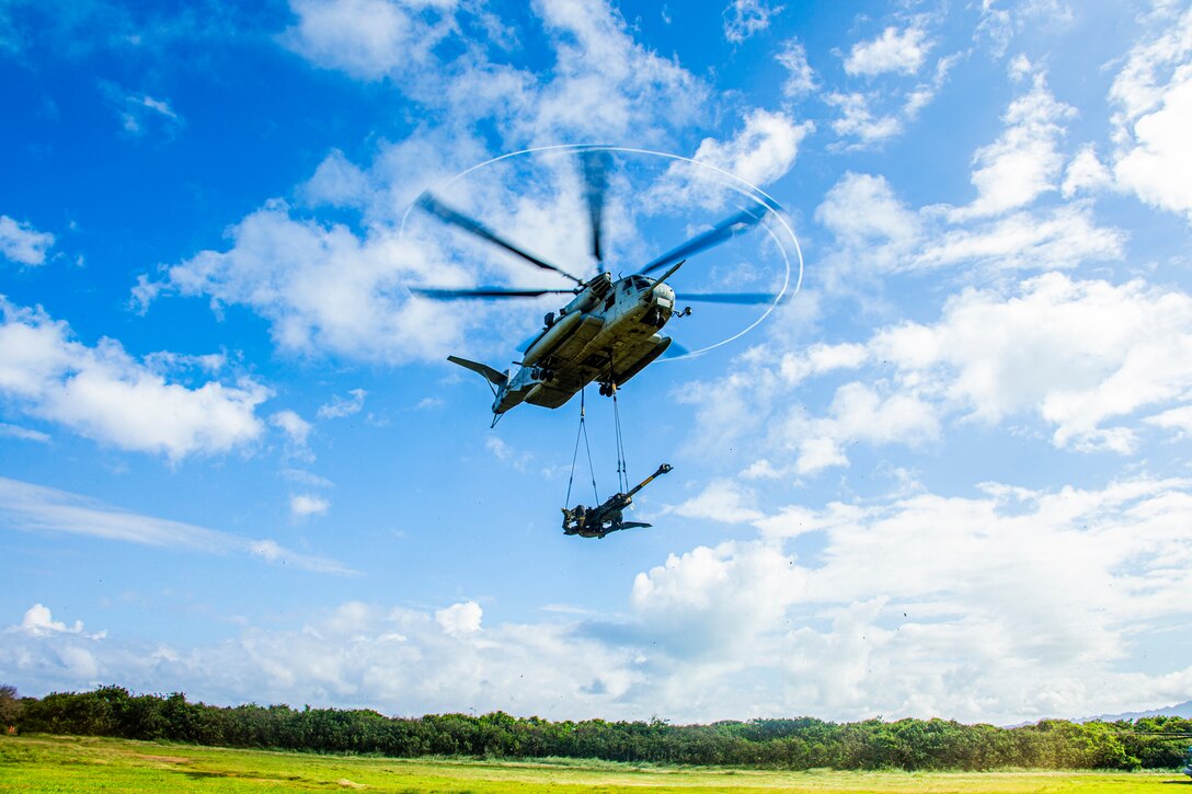 U.S. Marines with 1st Battalion, 12th Marines, 3d Marine Division, and Marine Heavy Helicopter Squadron 463 utilize a CH-53E to externally lift an M777 Howitzer on Marine Corps Base Hawaii, Jan. 13, 2022. 1st Battalion, 12th Marines and HMH-463 executed the operation in order to increase battlefield proficiency and combat readiness. (U.S. Marine Corps photo by Cpl. Jacob Wilson)